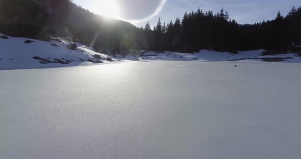 A drone shot over a snowy lake very low.