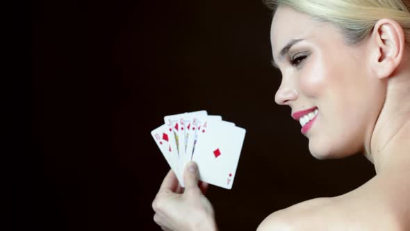 Young woman holding hand on cards and winking
