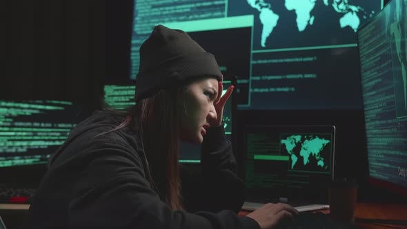 Young Asian Woman Hacker Using Computer Hacking And Upset, Code On Multiple Computer Screens