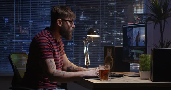 Young Man Sitting Back and Editing Video Inside a Room