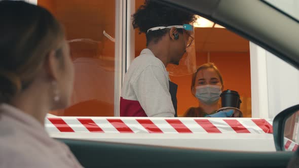 Close Up of Young Woman in Car Receiving Coffee in Drive Thru Fast Food Restaurant