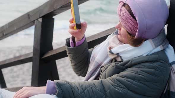 Woman Blogger in Warm Clothes Does Selphie on the Winter Beach