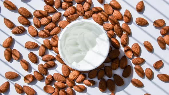 Zoom in Out Jar with Facial or Body Almond Moisturizer Jar Open with Almonds on the Table