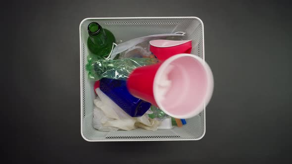 Throwing Plastic Garbage in the Metal Trash Can on Black Background