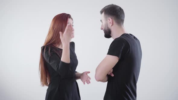 Young Irritated Caucasian Couple in Black Clothes Arguing at White Background. Handsome Bearded Man