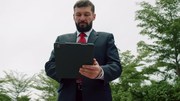 Portrait of a Serious Business Man Bearded Businessman in an Expensive Suit in a Red Tie Working on