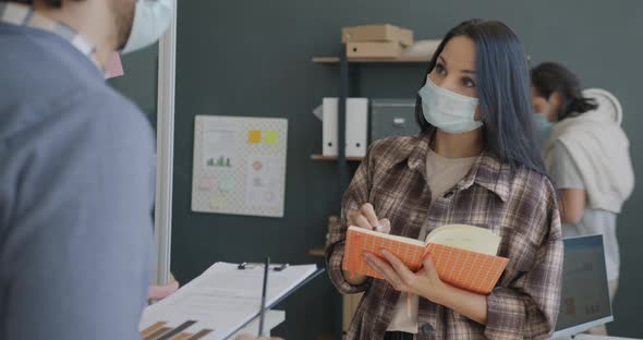 Young Woman Wearing Medical Mask Getting Orders From Boss Taking Notes in Office