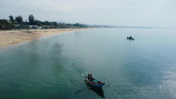 Unrecognizable fisherman operating boat with fishing net, Vietnam. Aerial circling