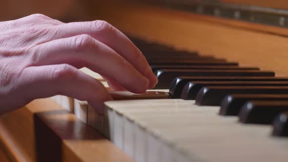 A Hand Plays One Chord On A Vintage Piano