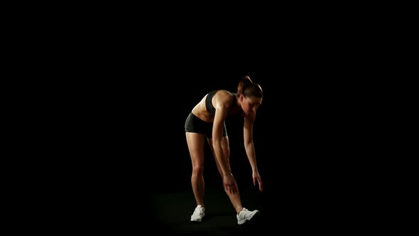 Young Athletic Woman Wearing Sporstwear is Warming Up Isolated on Black