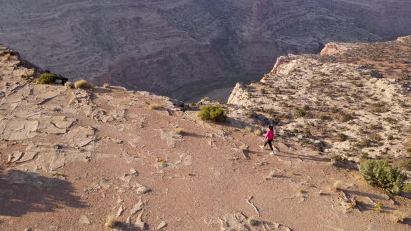 Aerial woman hiking on the edge of the San Rafael River Canyon in Utah