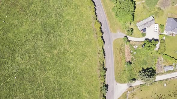 Overhead view of farmland with road adjacent to it and a car driving down the road. Sky view of farm