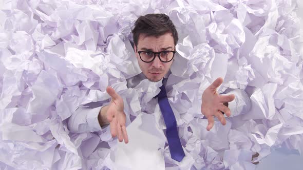 Awesome Man Office Worker in Glasses in a Large Heaps of Crumpled Paper