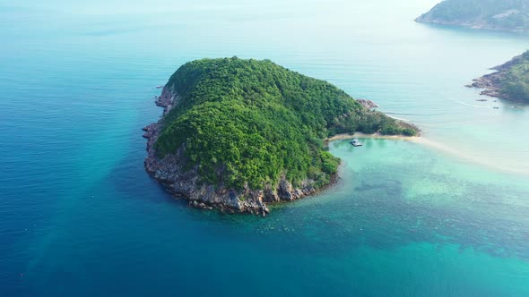 Thailand islands, aerial, Green cay with palms and rocky coast in the endless aquamarine ocean. Hear