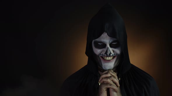 Sinister Man with Skeleton Makeup in Hood Making Angry Faces, Looking at Camera, Trying To Scare