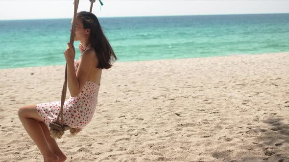 Happy Woman Enjoying Swing on Beach