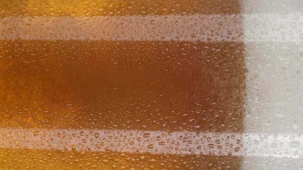 pour beer in glass close up and rotation. glass of beer with foam. vertical video. 4K UHD video