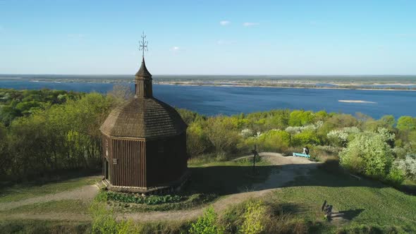 Flying Over Ancient Wooden Church in Vitachiv Village View of Hills Near Dnipro River at Sunset