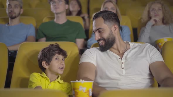 Portrait of Middle Eastern Father Closing Son's Eyes Looking at Inappropriate Scene in Film. Happy