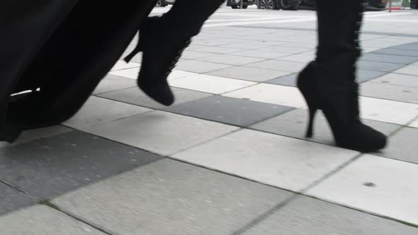 Female Legs of Models in Black and White Shoes Walk in the City Along a Tiled City Road