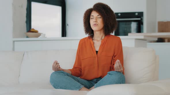 African Woman Calm Lady with Curly Hair Biracial Girl Sit Crosslegged on Sofa in Lotus Position