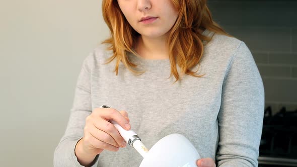 Woman adding ingredients to bowl for baking