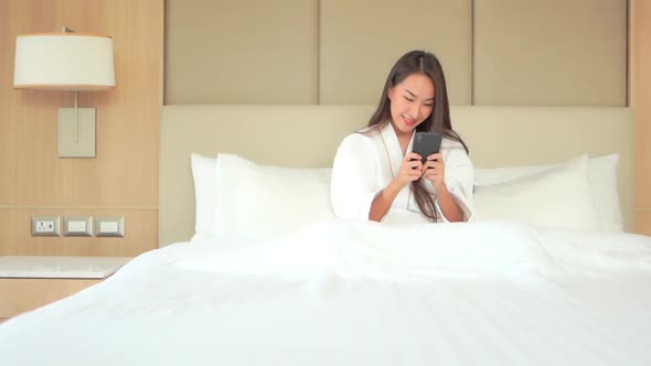 Pretty Asian Adult Woman Playing and Winning Game on Smartphone after Bath. Portrait of Smiling Asia