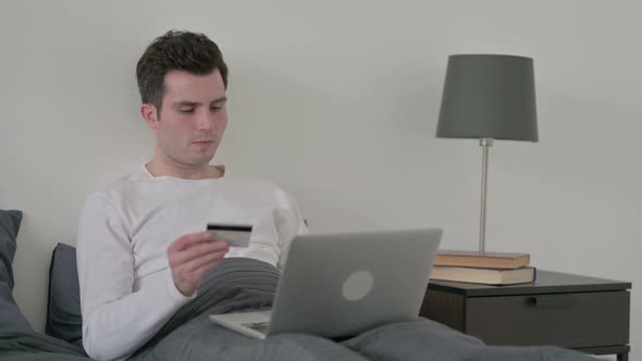 Man with Successful Online Payment on Laptop in Bed