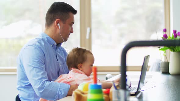 Father with Baby Working on Laptop at Home Office