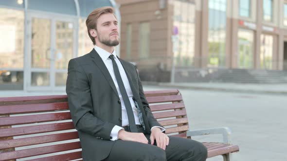 Businessman Having Back Pain While Sitting on Bench Outdoor