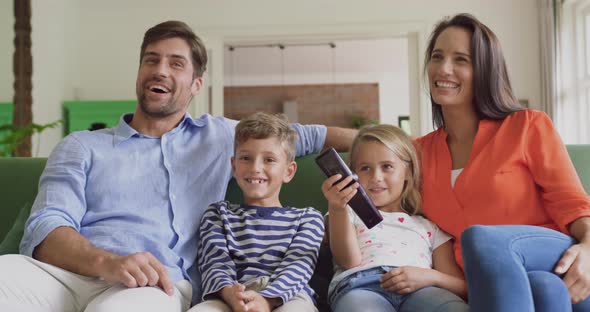 Family watching television together in living room at home 4k