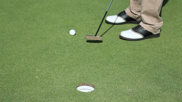 Mature man playing golf, low section