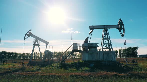 Two Working Oil Pumps in a Field By the Road