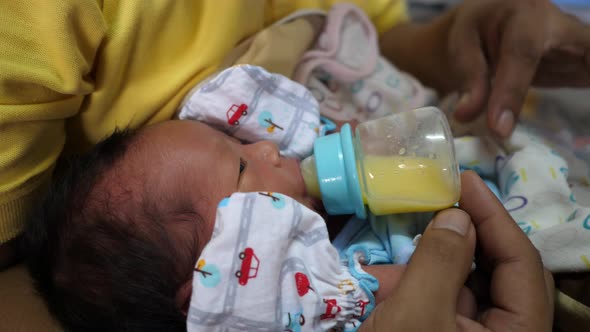 The newborn is eating breast milk from a bottle, slow-motion shot