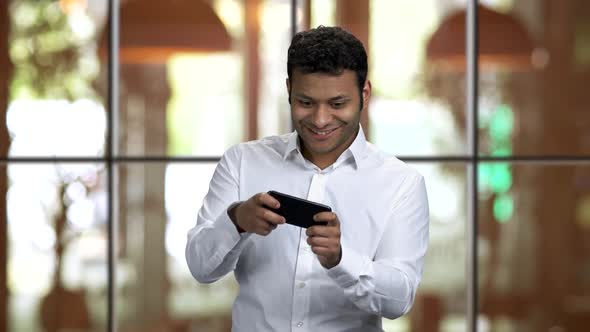 Excited Darkskinned Guy Playing Games on His Smartphone