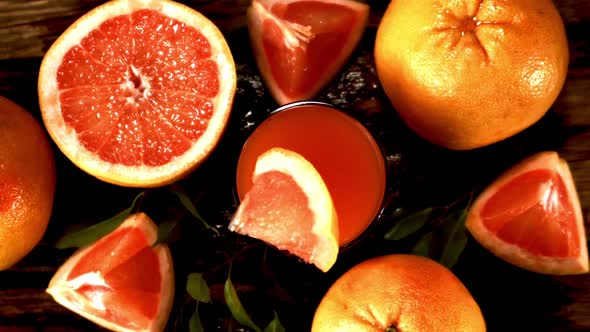 Super Slow Motion with Splashes a Piece of Grapefruit Falls Into a Glass of Juice