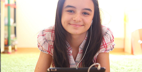 Smiling Girl Listening to Music on Digital Tablet