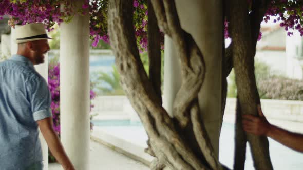 Happy Gay Couple Walking Between Columns in Summer Garden