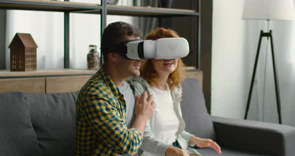 Couple Reacts Emotionally on Virtual Reality Images, Sitting on Sofa at Home