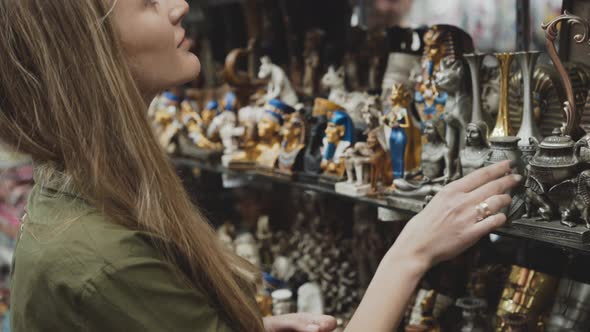 Pretty Girl Looks on Souvenirs at the Store for Tourists