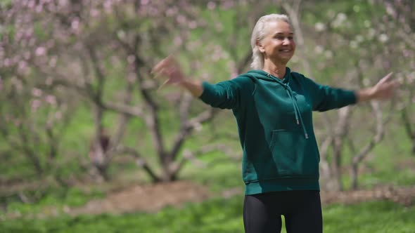 Fit Smiling Senior Sportswoman Exercising in Sunny Park on Summer Day