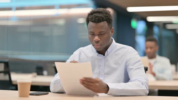 African Businessman Celebrating Success While Reading Documents