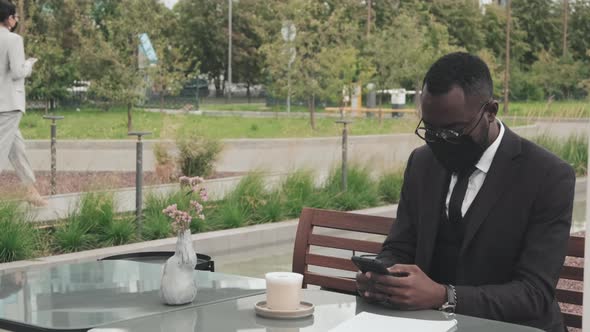 Businessman Using Mobile Phone in Outdoor Cafe