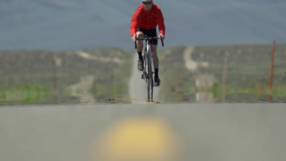 A man road biking on a scenic desert road.