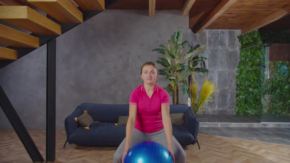 Sporty Fit Woman Squatting with Stability Ball Indoors