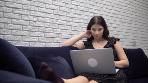 Attractive Woman Using Laptop on Sofa Couch Relaxing at Home