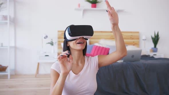 Portrait of Smiling Happy Young Woman Getting Experience Using VR Glasses at Home