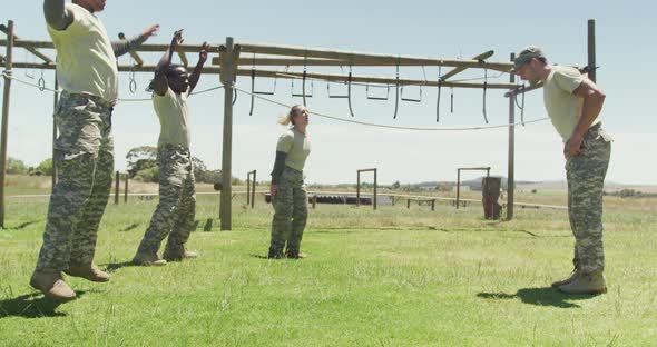 Fit diverse group of soldiers doing press ups after jumping jacks on obstacle course in the sun