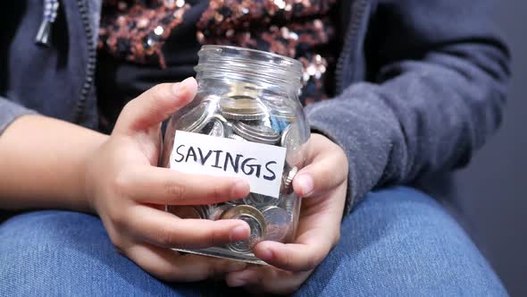 Child Girl Holding a Coin Jar While Sited