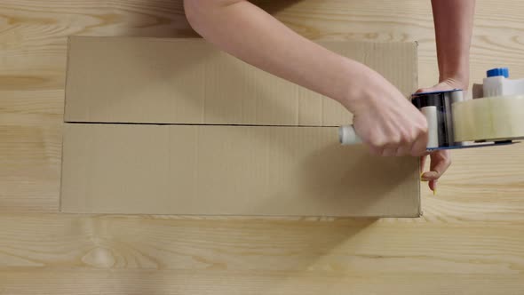 Young Female Online Store Owner Warehouse Worker Merchant Seller Seals with Tape Package Preparing